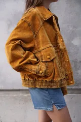 Campera estilo bomber o trucker de color mostaza/naranja quemado con efecto acid wash o desgastado. Presenta cuello camisero, cierre frontal y puños y cintura ajustados con elástico. Posee bolsillos frontales con solapa y botón.