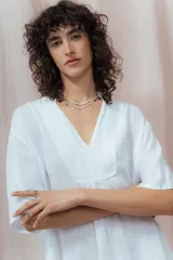 Vestido midi color beige de lino, corte amplio, escote en V y mangas cortas. Tiene dos volados en la falda.