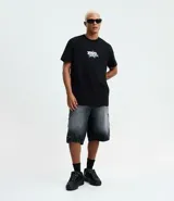 Remera negra de algodón con cuello redondo y mangas cortas. Presenta un estampado frontal con la frase "Divine Spark" y un estampado grande en la espalda de un ángel con halo y rayos celestes.