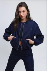Campera bomber corta de jean azul con cuello a la base, bolsillos ojal, mangas amplias abullonadas y pespuntes en rojo.