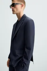 Blazer regular fit de hombre confeccionado en tejido con lana. Cuello con solapas de muesca, manga larga con puño abotonado, bolsillo de vivo en pecho, bolsillos de solapa en cadera, bolsillo interior, bajo con aberturas en espalda y cierre frontal de botonadura.