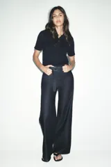 Chaqueta azul marino de punto con cuello subido y manga corta. Cierre frontal con botones.