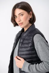 Chaleco acolchado color beige con cierre frontal y cuello alto.