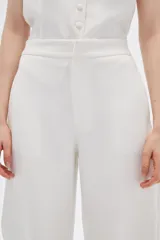 Pantalón blanco de poliéster, corte ancho, tiro alto y bolsillos laterales.