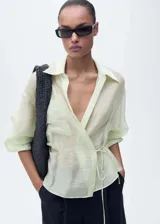Camisa color verde agua semitransparente con cierre de lazo en la cintura, diseño cruzado, bolsillo de parche en el pecho, cuello camisero y mangas largas.