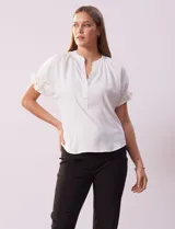 Blusa blanca de gasa con cuello a la base y escote en V. Mangas cortas y espalda con elástico fruncido.