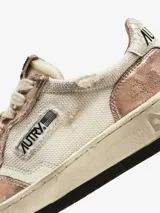 Championes urbanos Autry Super Vintage Low, color blanco con detalles en rosa metalizado y celeste. Confeccionados en cuero y tela, con efecto vintage y logo en el lateral.