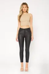 Pantalón jean engomado negro, de corte skinny y tiro medio.