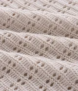 Camisa polo de manga corta, color beige claro, con textura de tejido abierto tipo ganchillo. Posee cuello y ribetes en las mangas en color azul marino.