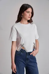 Remera blanca de algodón con cuello redondo y mangas cortas. Presenta apliques de strass en los laterales del ruedo.