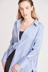 Camisa verde claro de corte recto y mangas largas con puños abotonados. Cierre frontal con botones.