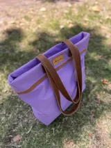 Bolso de lona color negro con detalles en cuero marrón, con bolsillo interno y forro de tela.