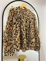 Camisa color camel con estampado animal print en negro, cuello mao y mangas largas con puños abotonados.