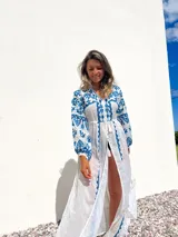 Túnica playera blanca traslúcida con bordados azules, mangas largas y abertura frontal.