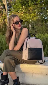 Mochila urbana color gris con detalles en cuero sintético negro. Cuenta con un compartimento principal amplio y un bolsillo frontal con cierre.