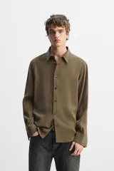 Camisa negra relaxed fit confeccionada en tejido fluido con mezcla de viscosa. Tiene cuello solapa, manga larga con puño abotonado y cierre frontal con botones.