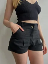 Short negro con cintura alta y bolsillos laterales, diseño ajustado.