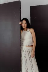 Conjunto de top y falda midi de punto color crema con ribetes negros. El top es ajustado, sin mangas y con cuello redondo. La falda es acampanada y con cintura elástica.