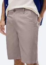Bermuda estilo chino de hombre, color gris oscuro o carbón, con tiro medio y largo hasta la rodilla. Presenta cierre frontal con botón y bolsillos laterales.