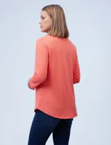 Blusa color coral con detalle de aros metálicos en el escote y manga larga.