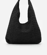 Bolso de playa tipo saco confeccionado en paja de papel color negro, con asa circular de metal dorado.