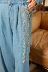 Pantalón denim gris con efecto lavado y detalles de pedrería en el frente, de corte amplio.