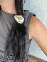 Colita de pelo plateada con aplique de metal ovalado.