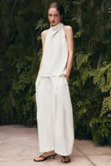 Top blanco satinado con cuello halter y escote fluido. Cierre en la espalda con botones.