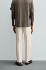 Pantalón de vestir color beige claro, corte regular fit, con pliegues frontales, bolsillos laterales y bolsillos traseros de vivo.