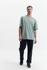 Remera de manga corta color verde con estampado de flores y texto en la espalda.