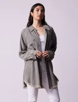 Camisa de jean celeste, marca Hester & Orchand, de corte oversize con cuello con solapa, escote en V y abertura central con botones. Delantera con bolsillos aplicados, mangas largas regulables con presilla y botón, y ruedo desflecado.