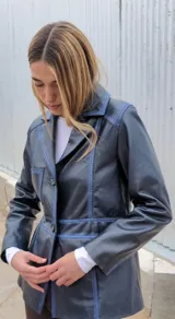 Blazer azul marino gastado, con cuello de solapa, cierre con botones y bolsillos laterales.