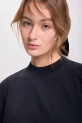 Remera negra de corte holgado, con cuello alto y mangas 3/4.