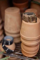 Cinto de cuero color beige con hebilla metálica de doble argolla y detalles de tachas redondas en el mismo tono.