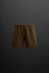 Bermuda jogger color marrón confeccionada en tejido de algodón con interior de rizo. Tiene cintura elástica ajustable con cordón y bolsillos laterales.