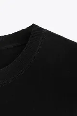 Top negro de punto con cuello redondo y manga corta.