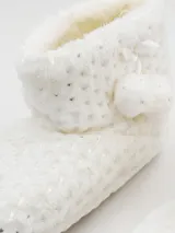 Pantuflas tipo bota color blanco con interior de felpa y detalle de moño y pompón.