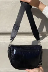 Bandolera de cuero celeste con correa de cinta regulable, forro de algodón, cierre central y bolsillo trasero con cierre.