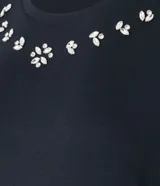 Remera negra de viscosa con cuello redondo y mangas cortas. Presenta apliques de strass en el escote.