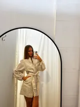 Mono corto de lino color beige claro, con cuello mao, cierre frontal, mangas globo largas y cinto para ajustar a la cintura.