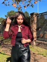 Chaqueta corta de jean color bordó, con cuello camisero, mangas largas y bolsillos con solapa en el pecho.
