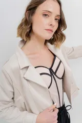 Chaqueta color beige de tela tipo gamuza con elastano, cuello solapa, manga larga con trabillas en hombro, bolsillos delanteros con cremallera metálica y cierre frontal con cremallera.