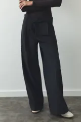 Pantalón negro de tiro alto, corte ancho y largo midi. Incluye bolsillos delanteros, pinzas y cinturón de la misma tela.