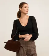 Blusa negra de punto con escote en V y mangas largas abullonadas con detalles de encaje.