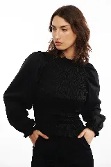 Blusa negra con punto smock, confeccionada en algodón 100% con mangas abullonadas y cuello redondo.