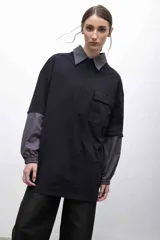 Remerón negro oversize con cuello camisero gris, mangas largas grises con puños elásticos, bolsillo con tapa en el pecho y logo bordado.