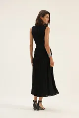 Vestido midi negro de lino, sin mangas, con escote redondo y falda fruncida. Incluye cinturón de cuero trenzado con hebilla metálica.