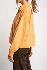 Sweater color naranja con cuello polo y botones, de corte holgado y mangas largas.