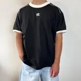 Remera negra de corte regular con cuello redondo y ribetes en contraste color blanco en el cuello y los puños. Presenta un pequeño logo bordado en el pecho.