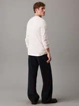 Remera color crema de punto gofrado con cuello redondo, mangas largas, puños de canalé e insignia con el logo de Calvin Klein en la manga.